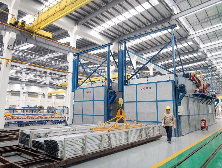 Aluminium profile bundles in front of ageing ovens on a factory floor
