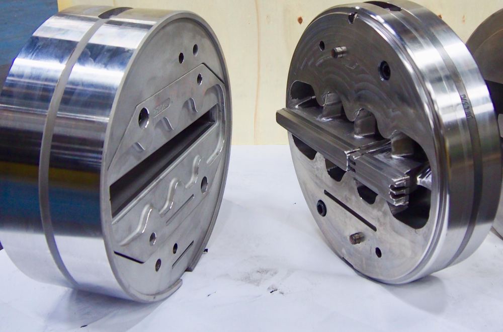 Two aluminium extrusion dies showing feeder ports and bearing surfaces